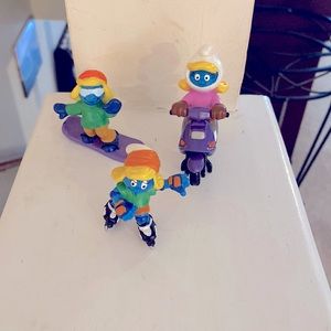 Smurfette action figurines.  Roller skating, driving a scooter and snow boarding